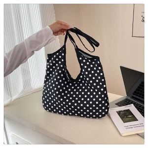 Detail view of large capacity black canvas tote bag with white polka dots pattern