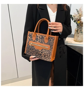 Detail of leopard print tote bag with brown leather trim and front zipper pocket detail