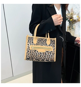 Fashionable leopard print tote bag with camel handles held by model in black suit