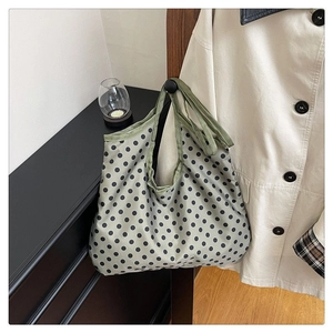 Detailed close-up of a green polka dot canvas tote bag hanging in a cozy home setting