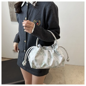 Primer plano de bolso blanco con cordón, estampados de mariposas verdes y textura plisada