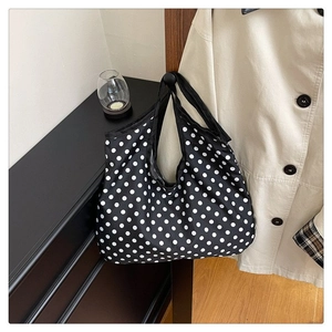 Detailed view of large black polka dot tote bag hanging in a minimalist home setting