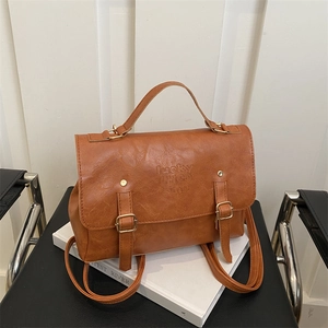 Detail of a brown vintage PU leather backpack with buckle straps and embossed logo