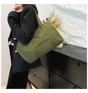 Detail of army green nylon tote bag featuring front zipper pocket and long handles