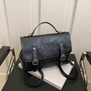 Close-up of black vintage PU leather backpack featuring golden buckles and embossed logo
