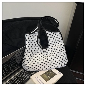 Detailed view of canvas tote bag with black polka dots on black corduroy background