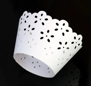 Detailed laser-cut white cupcake wrappers with elegant floral patterns and scalloped edges