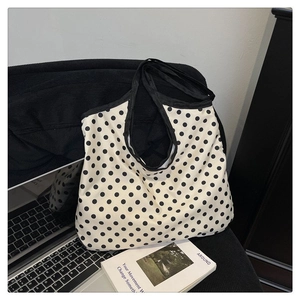 Detailed view of polka dot canvas tote bag with black piping on a cozy background