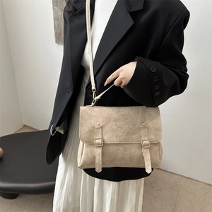 Close-up of beige vintage flap crossbody bag with vertical buckles and embossed logo