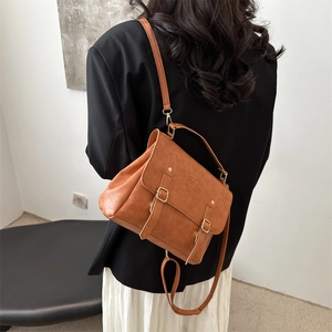 Side view of a vintage brown leather backpack with metal buckles and Lucky COCO logo