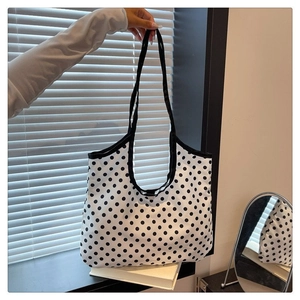 Detailed close-up showing the black polka dot pattern on a large white canvas tote bag