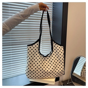Detailed close-up of a large black polka dot canvas tote bag held in hand for daily use