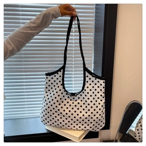 Detail of a large canvas tote bag with black and white polka dots and reinforced straps