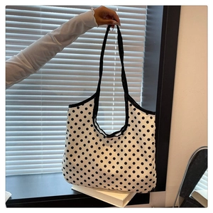 Close-up of black polka dot pattern and durable woven handle on white canvas tote bag