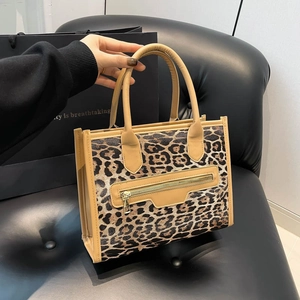 Retro leopard print tote bag with brown handles and gold zipper detail on leather chair