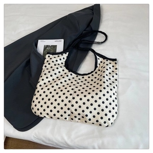 Detailed view of large black polka dot canvas tote bag against a minimalist magazine background