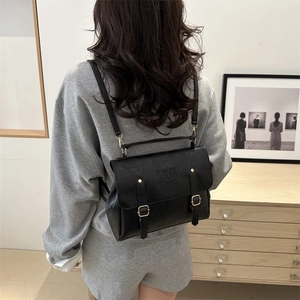Detail view of vintage black leather backpack with gold buckles worn by a model
