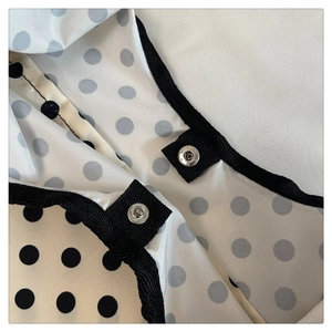 Detail of a polka dot canvas bag with black herringbone binding and a silver snap button