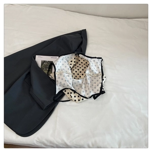 Detail of minimalist black and white polka dot fabric paired with a dark grey blazer jacket