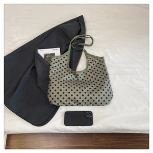 Flat lay of green polka dot tote bag with long handles alongside lifestyle accessories