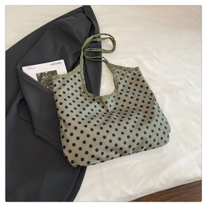 Detail of light green polka dot canvas tote bag shown with a magazine on white fabric