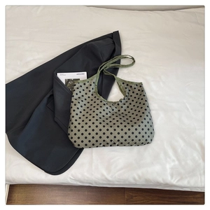 Detailed view of large green canvas tote bag with black polka dots on white fabric