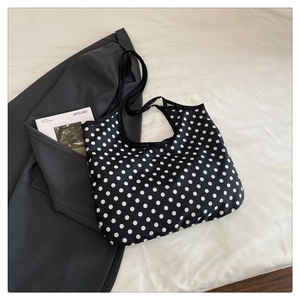 Detailed close-up of large polka dot canvas tote bag on soft white bedding background