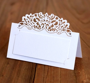 Détail de la dentelle découpée au laser sur d'élégantes cartes de place de mariage blanches