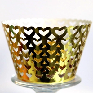 Elegant laser-cut gold cupcake wrapper with heart patterns and scalloped edges for weddings