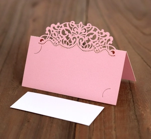 Détail du marque-place de mariage rose découpé au laser avec motif de dentelle élégant