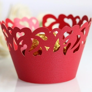 Intricate laser-cut red cupcake wrapper with heart patterns for festive wedding decoration