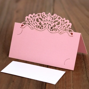 Marque-place en dentelle découpée au laser avec insert blanc sur table en bois