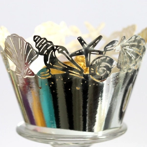 Elegant laser-cut silver metallic cupcake wrappers with ocean shell and starfish patterns