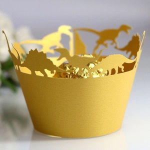 Laser-cut gold paper cupcake liners with dinosaur silhouette patterns for party decor