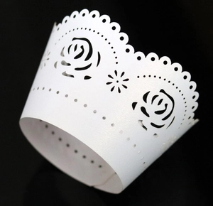 Close-up of white laser-cut cupcake wrapper with pearl paper rose floral patterns