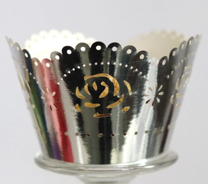 Macro detail of laser-cut silver rose pattern cupcake wrappers with reflective mirror finish