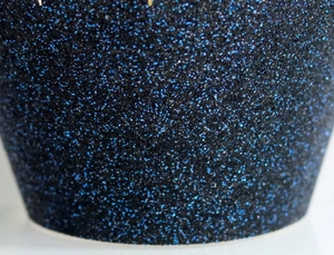 Macro shot of fine blue glitter texture on black cupcake wrapper birthday decorations