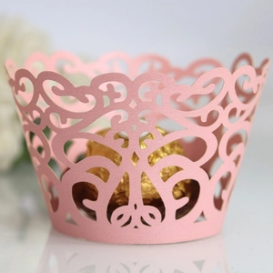 Pink laser-cut cupcake wrappers with elegant scroll patterns for party dessert table decoration