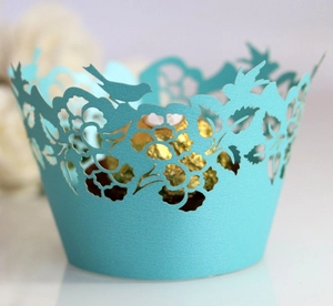 Detail of laser-cut light blue cupcake wrappers with bird patterns and floral lace