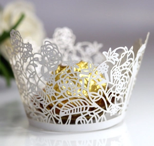 Macro detail of laser-cut white cupcake wrapper with elegant rose and leaf pattern
