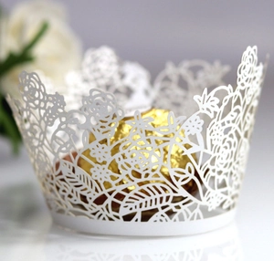 Macro detail of laser-cut white cupcake wrappers with elegant floral rose patterns