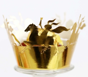 Macro detail of laser-cut golden cupcake wraps with knight and horse silhouettes