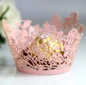 Detailed macro view of laser-cut pink paper cupcake liners with elegant floral patterns
