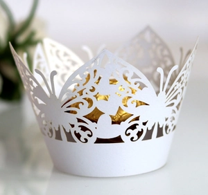 Detailed laser-cut butterfly cupcake wrapper in white with elegant scroll patterns