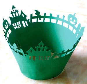 Detail of laser-cut green Halloween cupcake wrappers with castle and pumpkin patterns