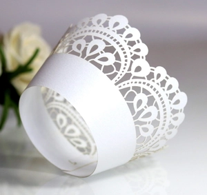 Detailed close-up of white laser-cut crown lace cupcake wrapper with pearl finish