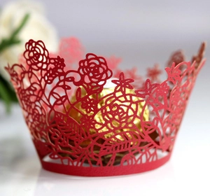 Macro view of laser-cut red rose pattern cupcake wrappers for wedding parties