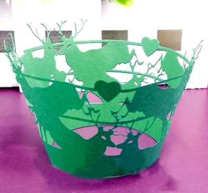 Detail of green laser-cut cupcake wrapper featuring woodland reindeer and heart patterns