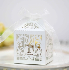 Detail of white laser-cut wedding candy box with bird pattern and silk ribbon ties