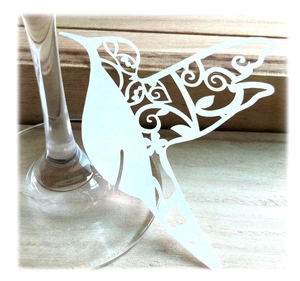 Elegant laser-cut white hummingbird paper place card on a wine glass for weddings